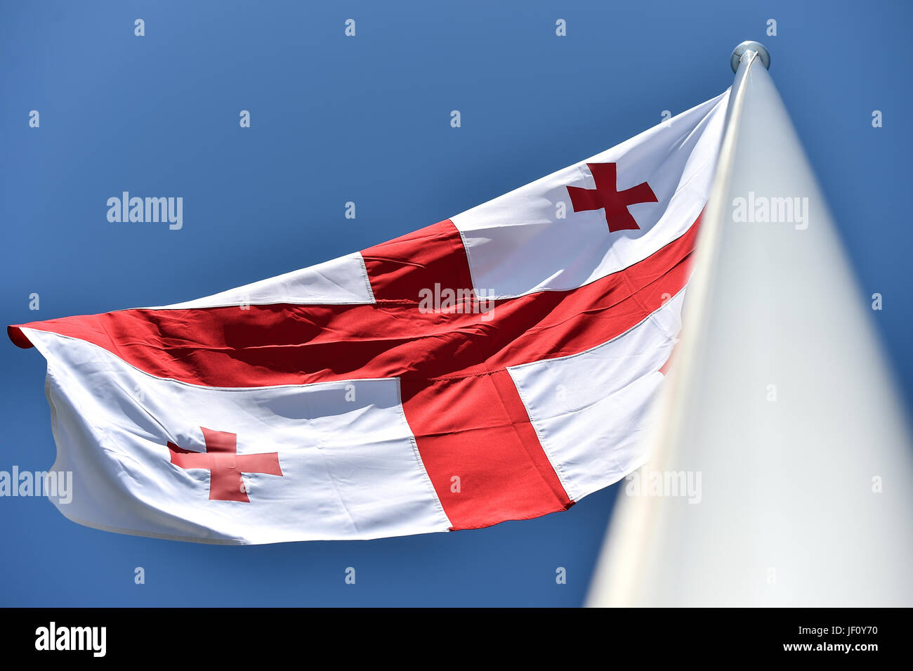 La Georgia bandiera nazionale soffiata dal vento contro un cielo blu Foto Stock