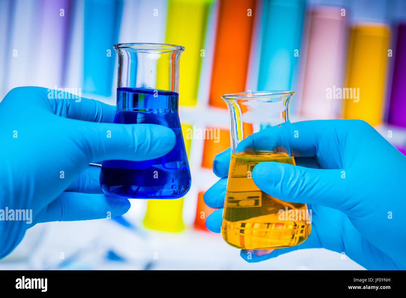 Il tecnico confronta due beute con sostanze colorate in un laboratorio. La chimica e la scienza delle apparecchiature. Foto Stock