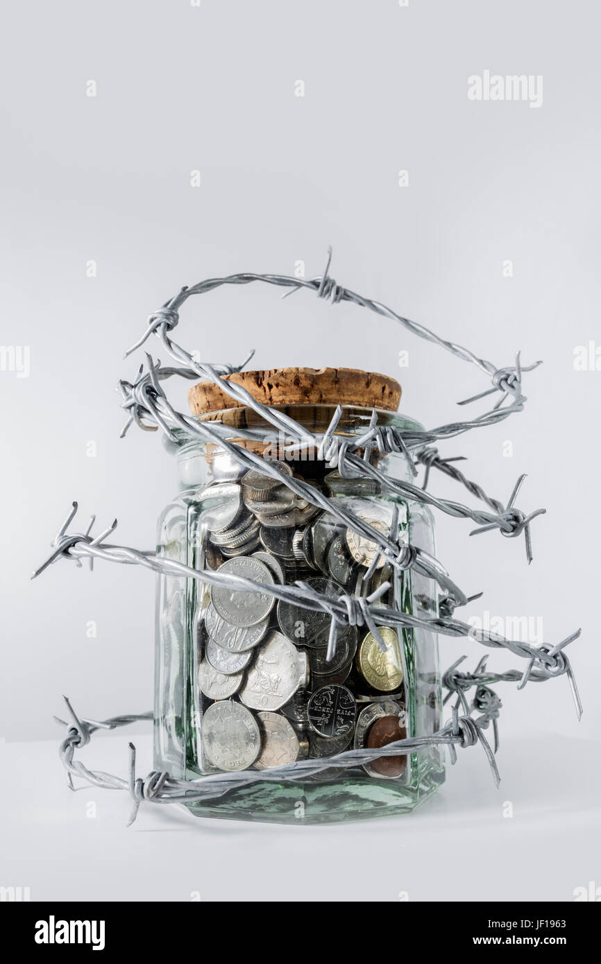 Il vaso pieno per metà del denaro circondata da filo spinato. Foto Stock