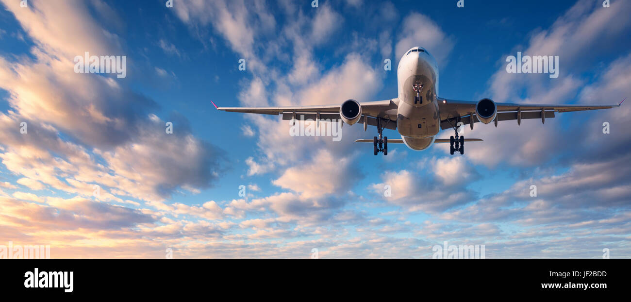 Atterraggio aereo. Paesaggio con bianco aereo passeggeri vola nel cielo blu con nuvole al tramonto colorato. Sfondo di viaggio. Airli passeggero Foto Stock