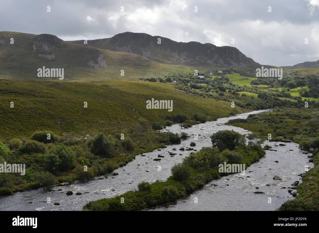 Piccolo fiume che scorre nella verde vegetazione e paesaggio di montagna in una strada nazionale in Irlanda Foto Stock