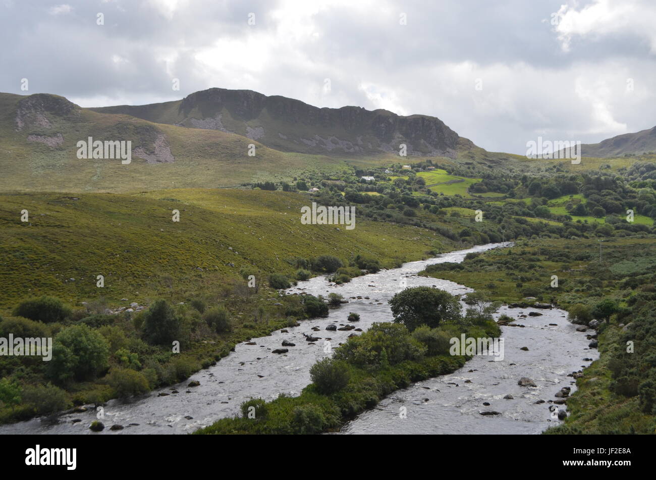 Piccolo fiume che scorre nella verde vegetazione e paesaggio di montagna in una strada nazionale in Irlanda Foto Stock