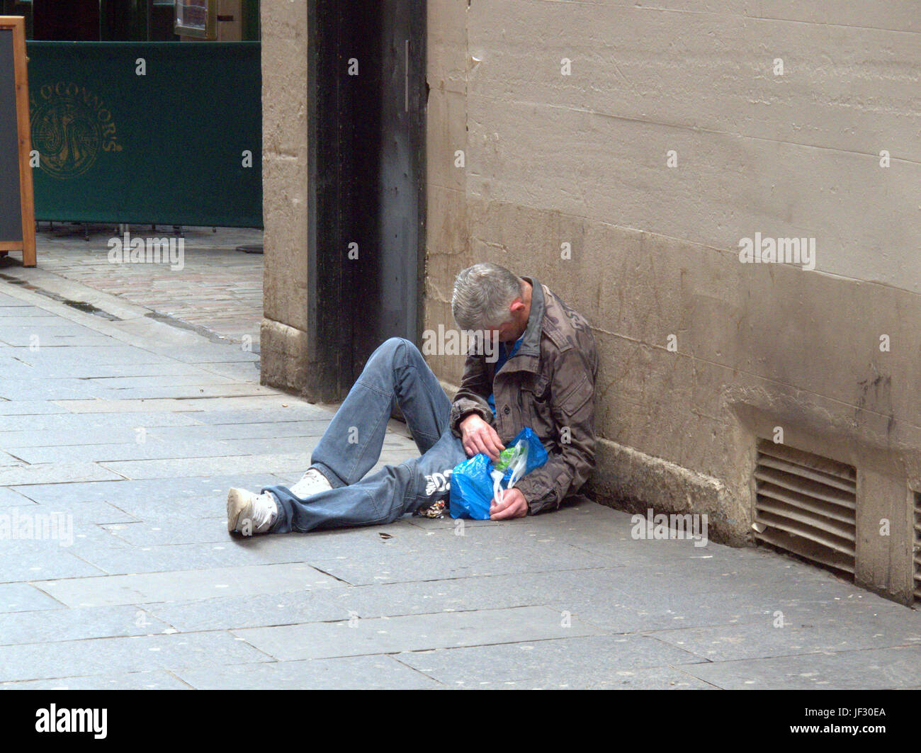 Mendicare senzatetto disoccupati uomo disteso sulla strada inconscio Foto Stock