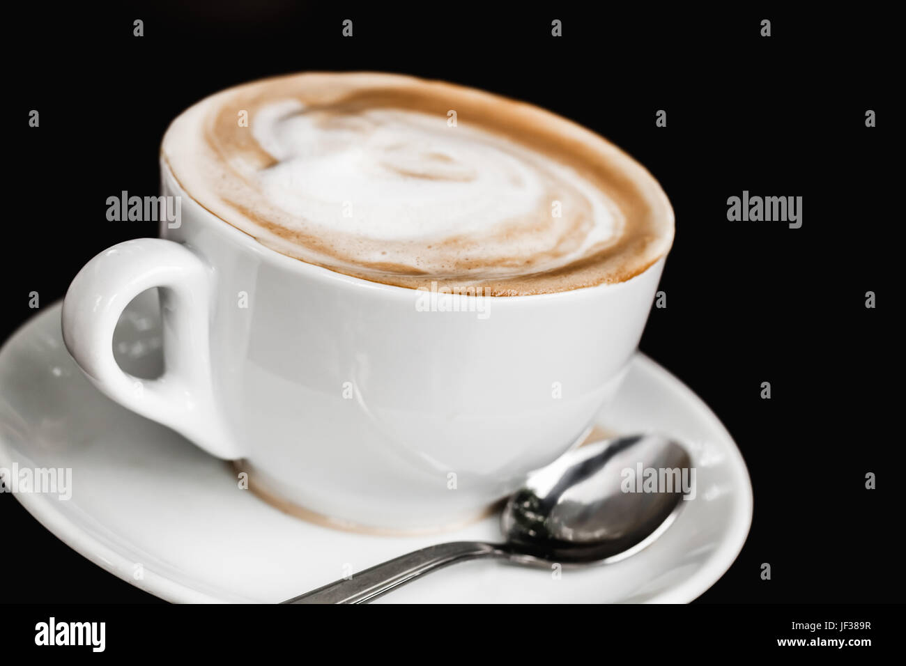 Tazza di cappuccino. White la tazza di caffè con la schiuma di latte sul nero sfondo tabella, closeup foto con messa a fuoco selettiva Foto Stock