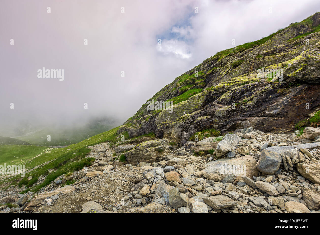 Bordo del ripido pendio sulla collina rocciosa nella nebbia meteo. lo scenario spettacolare in montagna Foto Stock