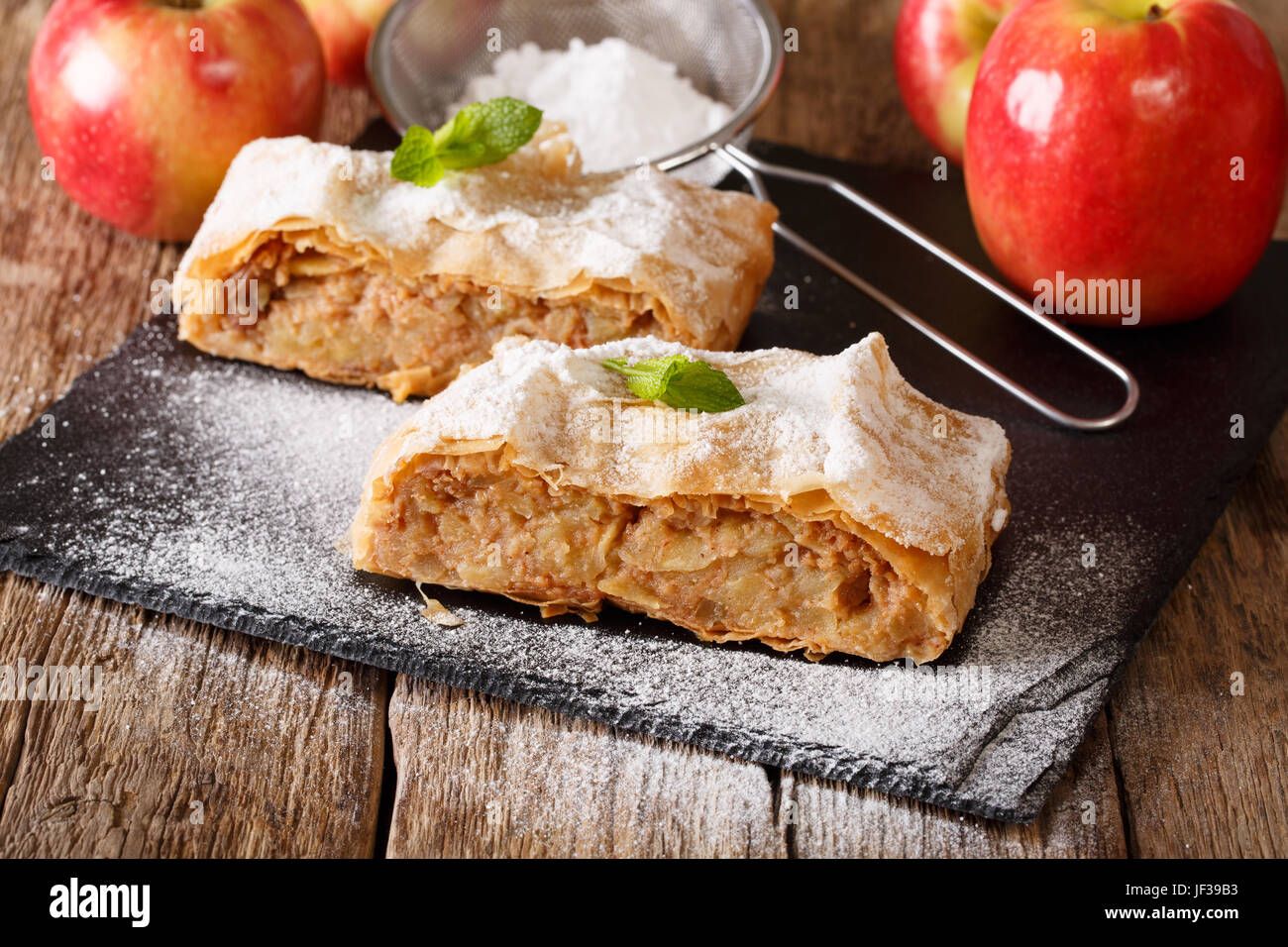 Deliziosa fetta di strudel di mele con zucchero a velo e menta closeup su una tavola orizzontale. Foto Stock