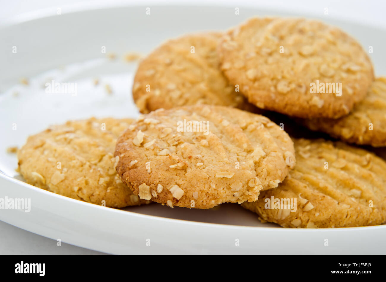 Friabili biscotti di avena (cookies) su una porcellana bianca piastra con briciole visibile. Foto Stock