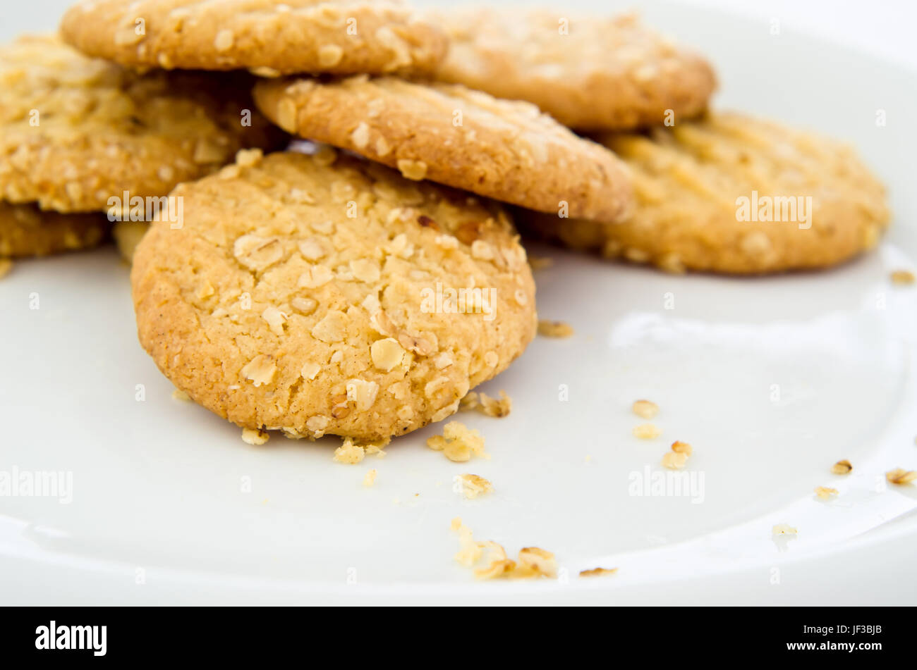 Una piastra bianca di pane appena sfornato, friabili biscotti di avena (cookies), con le briciole. Foto Stock
