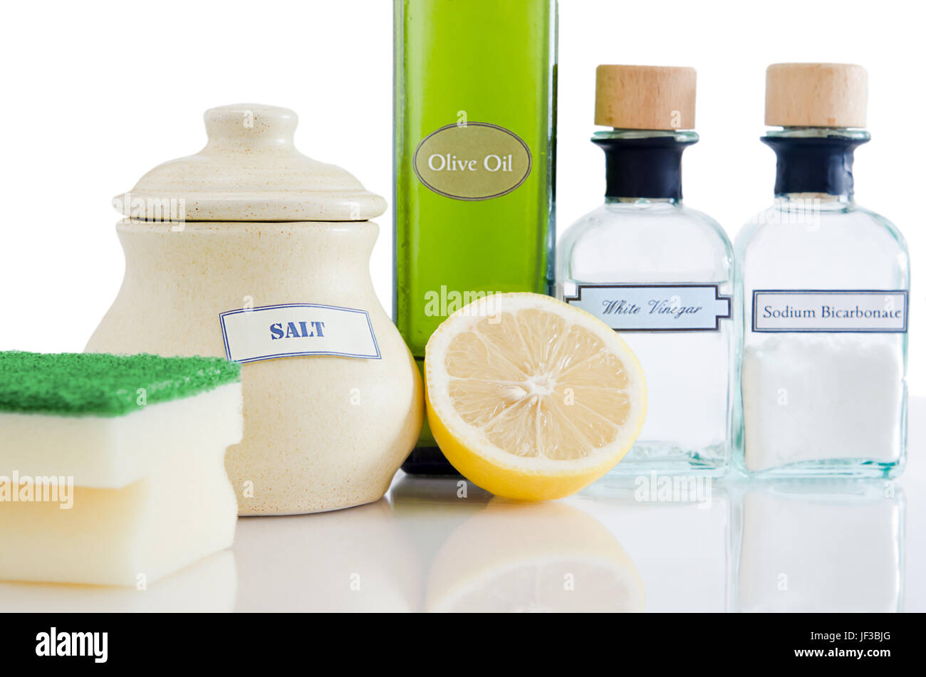 Una gamma di naturale, non tossico di prodotti per la pulizia in contenitori su un lucido superficie riflettente con uno sfondo bianco. Foto Stock