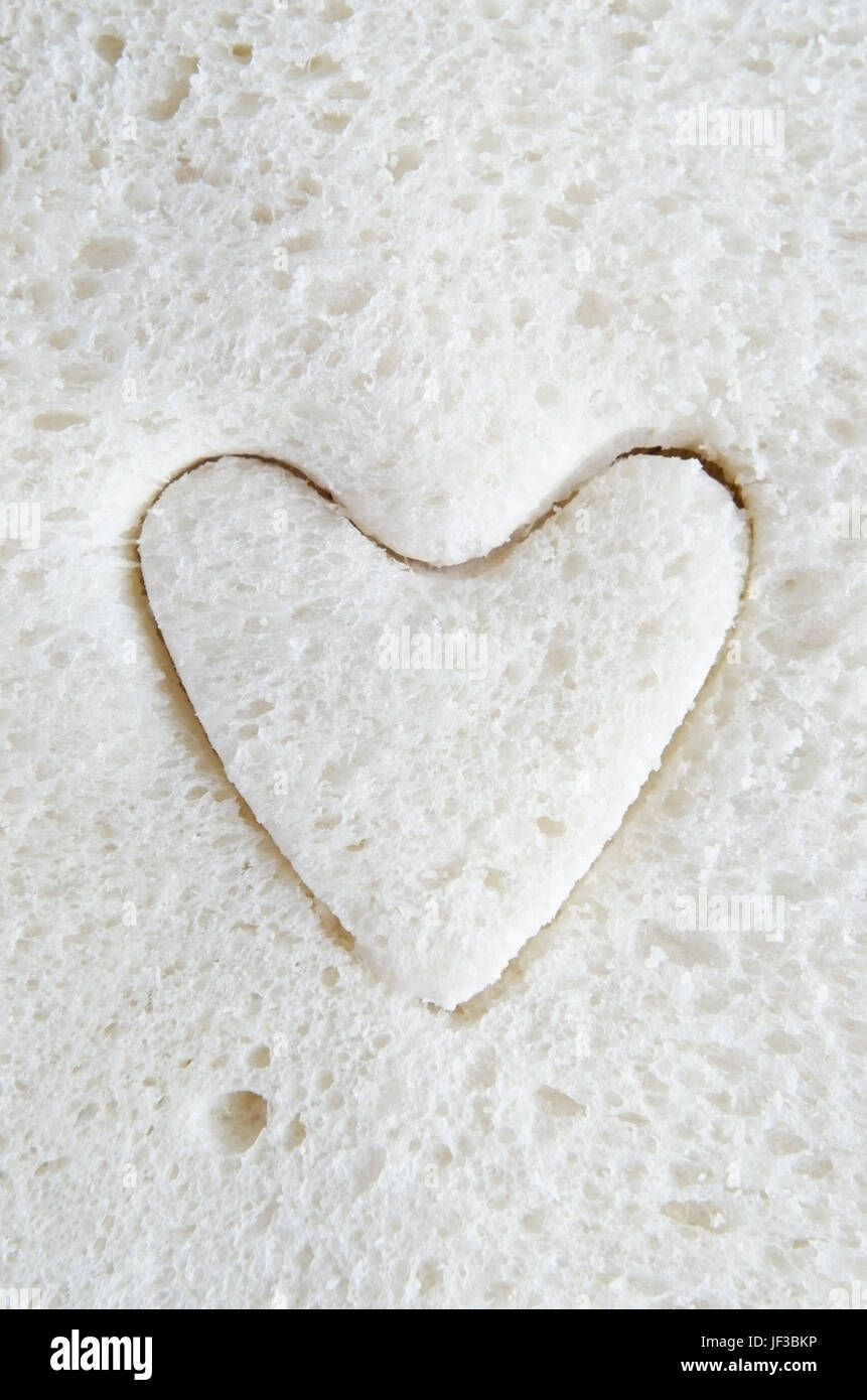 Close up (macro) di pane bianco con una forma di cuore tagliato in esso. Foto Stock