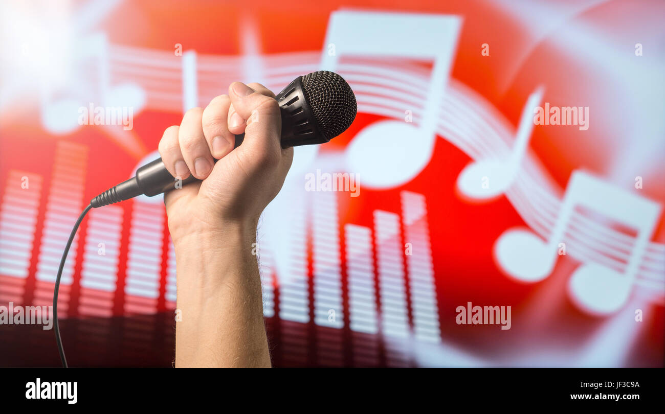 Il canto, karaoke o vocal concetto di formazione. Microfono in mano davanti a un abstract di musica nota a tema e sfondo dell'equalizzatore. Song Contest e li Foto Stock