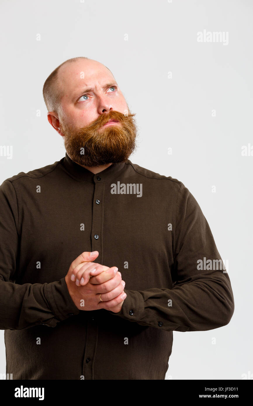 Malinconici Uomo in camicia marrone con zenzero barba e baffi sul vuoto lo sfondo grigio Foto Stock