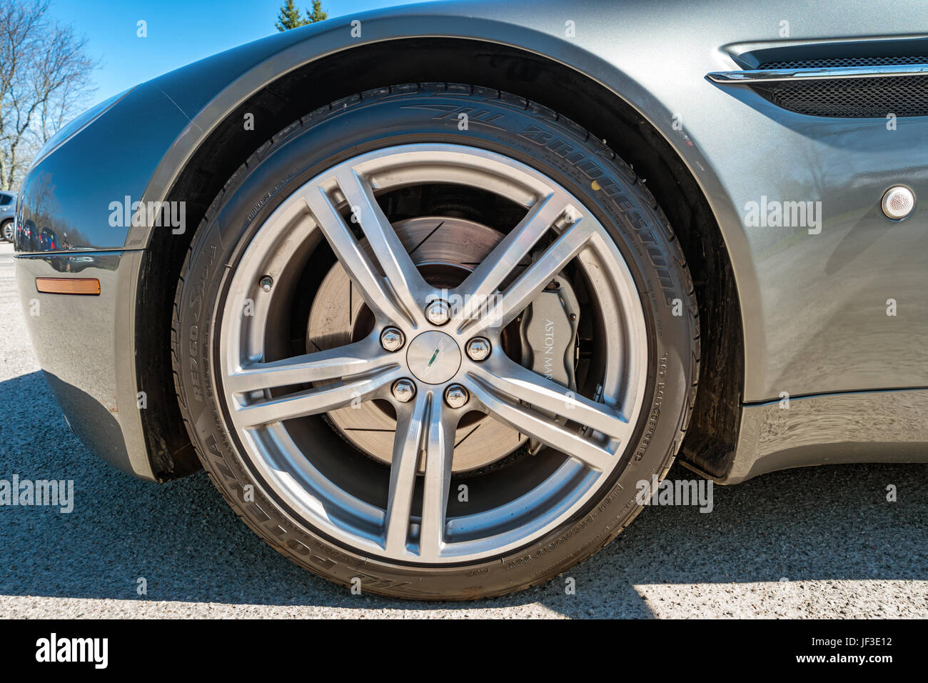 Una ruota con cerchione e pneumatico di una Aston Martin Vantage V8 coupé sportiva di lusso auto parcheggiate in un parcheggio di Hamilton, Ontario. Foto Stock