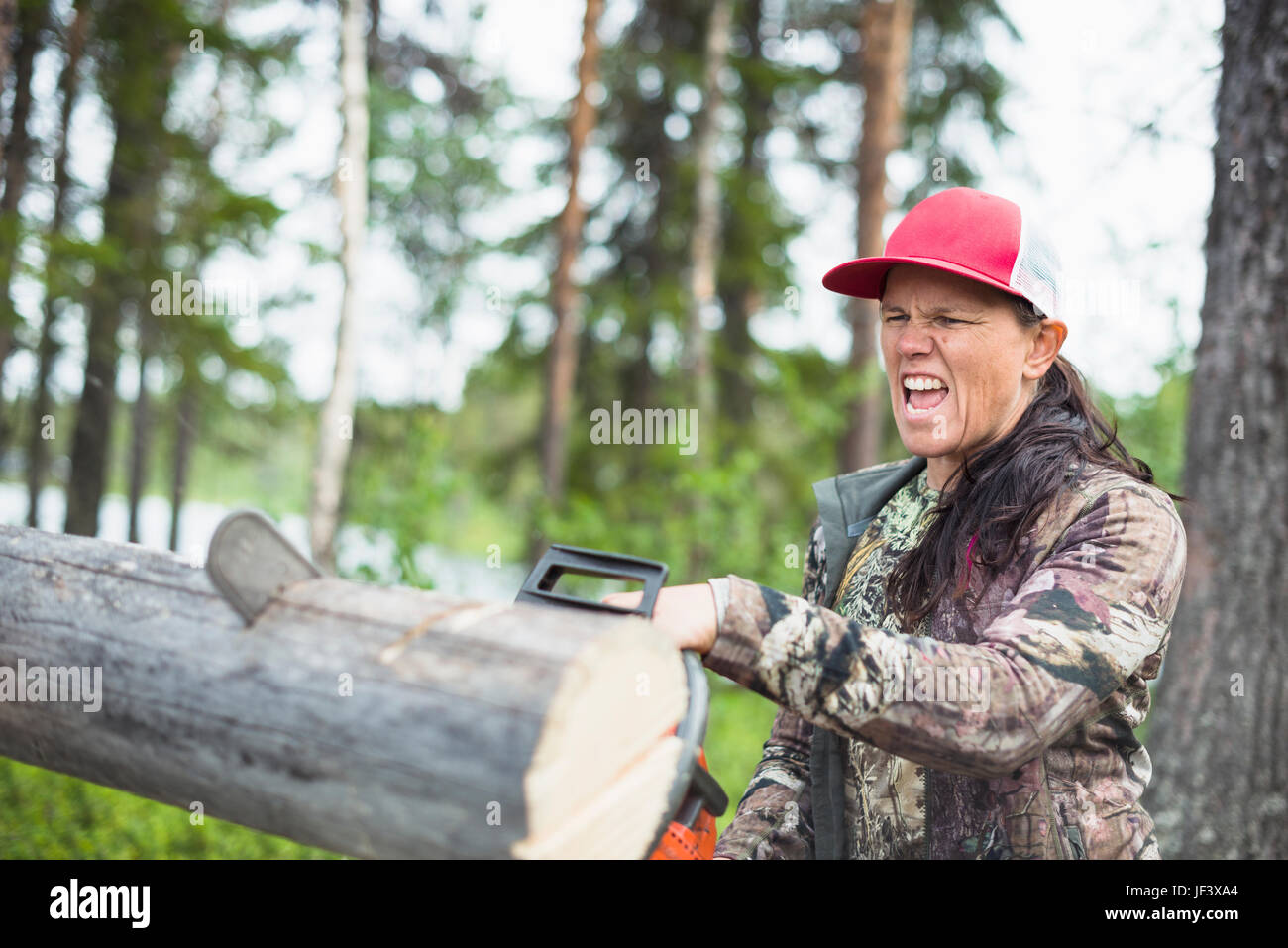 Donna che utilizza chainsaw Foto Stock