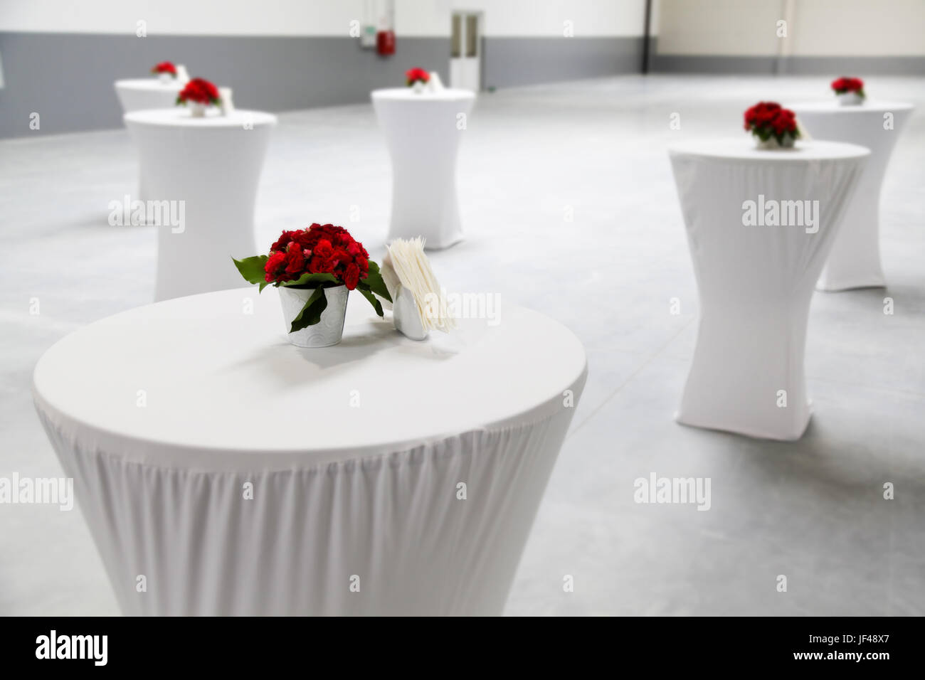 Decorazione di evento con rosso fiori posto sul top bianco tabelle Foto Stock