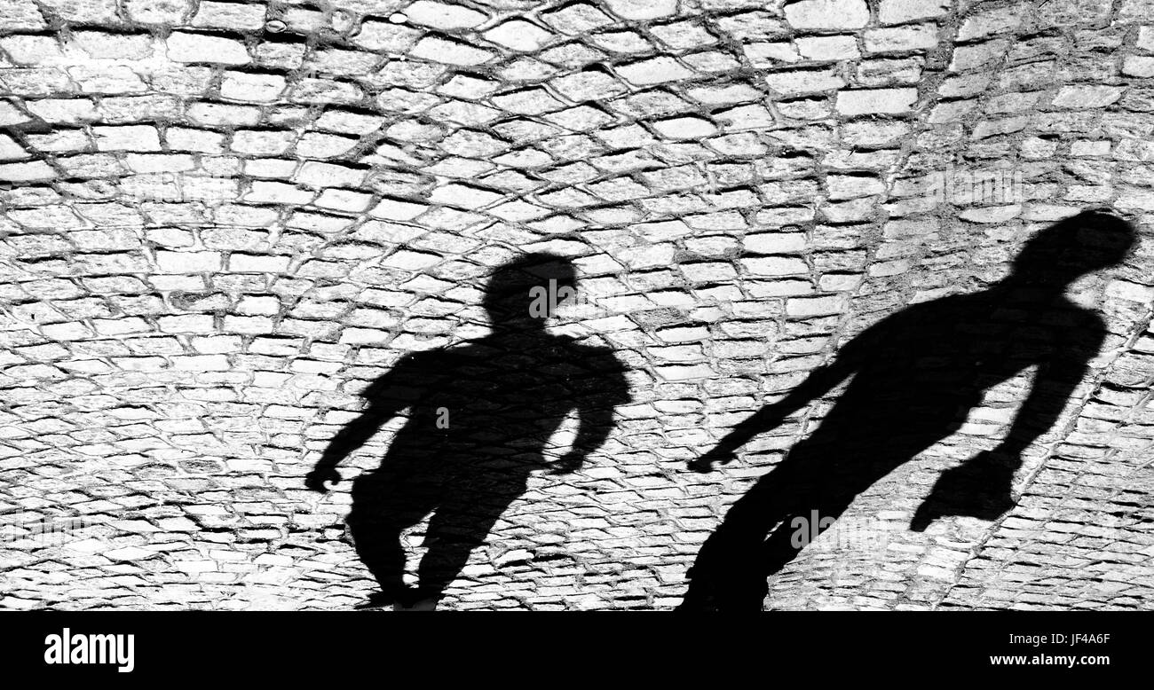 Le ombre di due persona sulla vecchia strada di ciottoli in bianco e nero; Foto Stock