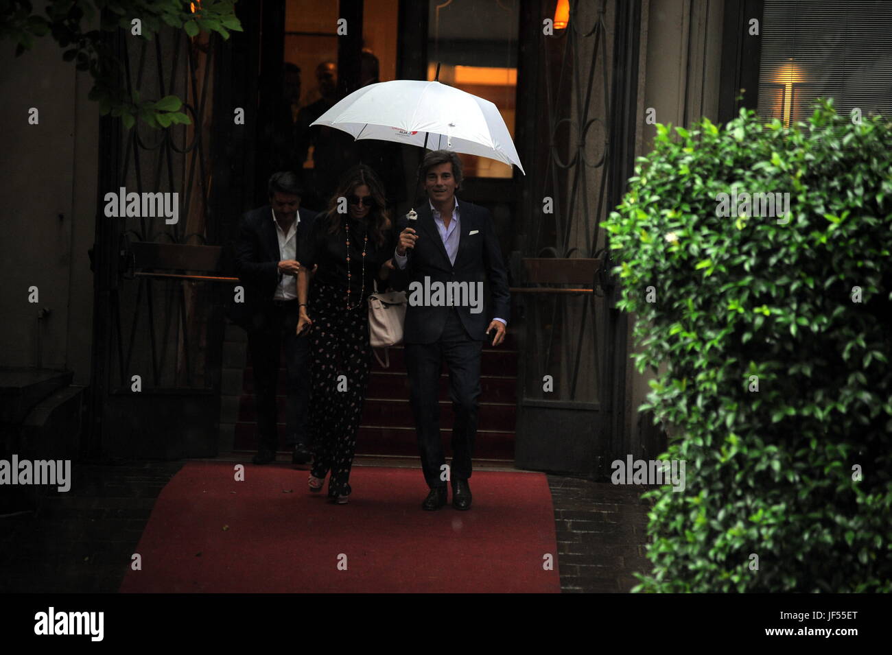 Milano, Daniela Santanche e Dimitri lasciare il ristorante sotto le inondazioni Daniela SantanchÃ" e il suo fidanzato Dimitri andare a pranzo al "baretto". Come si può uscire, un autentico diluvio è innescato, e decidono di attendere alcuni minuti. Ma la pioggia non si ferma, in modo che il proprietario del ristorante dà Daniela SantanchÃ¨ un ombrello per essere riparato. I due entrano insieme sotto il braccio, Dimitri riparazioni elegantemente la SantanchÃ" fino a che non entra in contatto con la macchina e poi sia lui che il loro corpo di guardia-driver andare fino a lasciare. Foto Stock