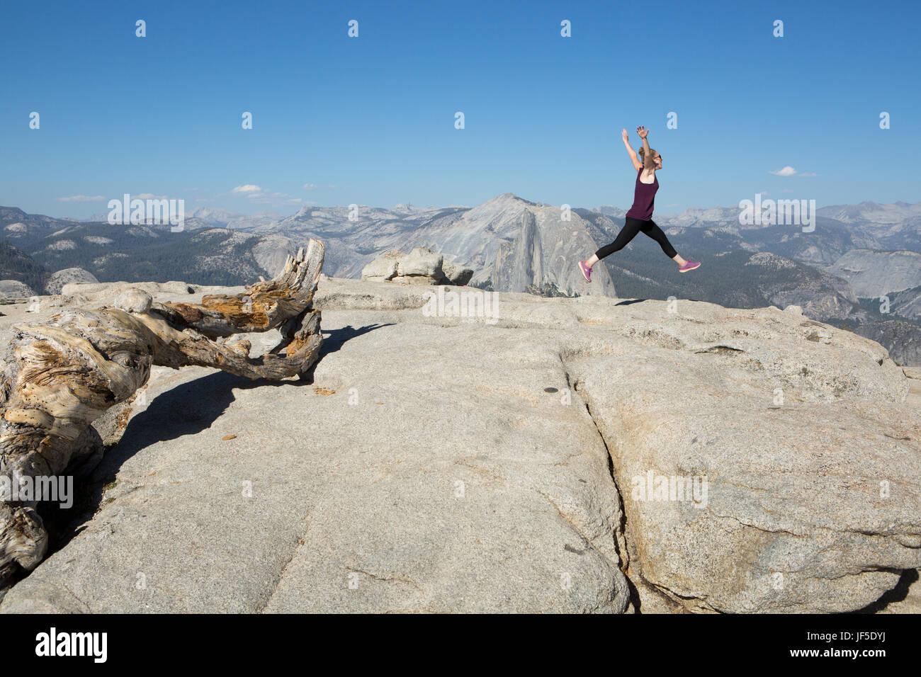 Un escursionista graziosamente salti, in un balletto motion, sulla cima di Sentinel Dome, un picco roccioso che offre splendide vedute sulla valle di Yosemite. Foto Stock