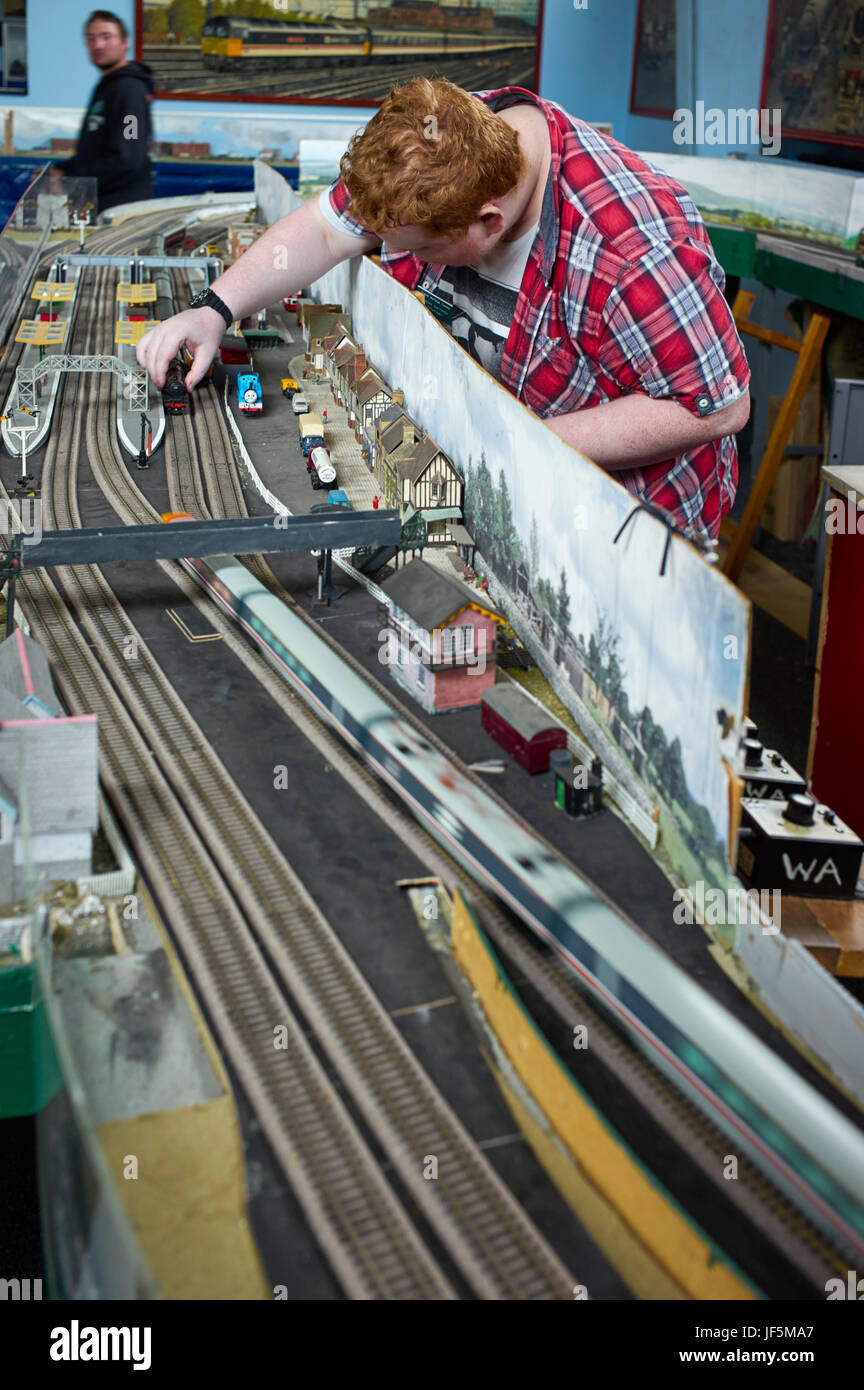 L'uomo l'impostazione modello di treno sulla traccia del layout Foto Stock