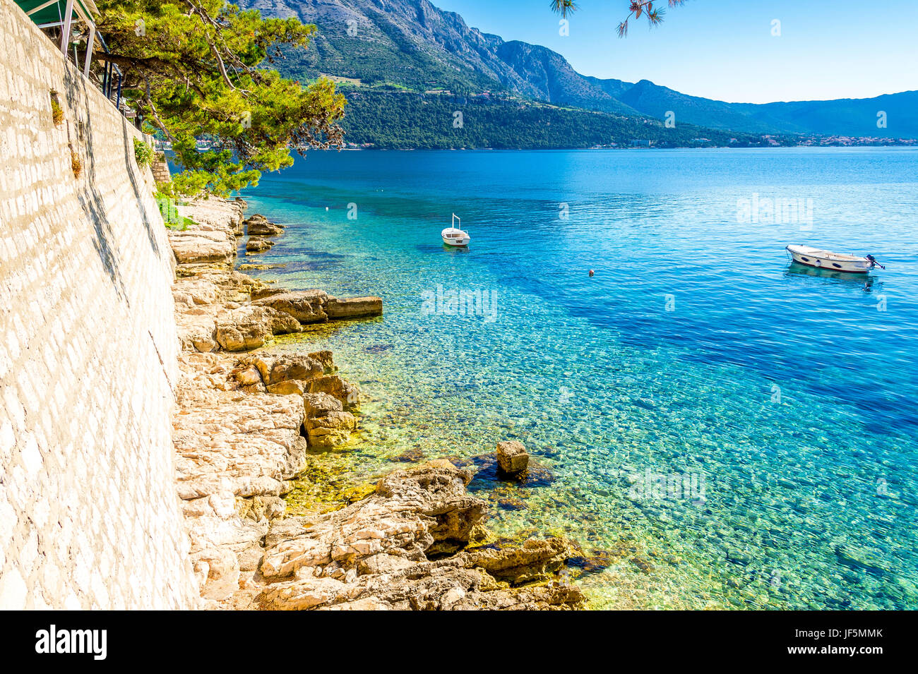 La spiaggia di Zakerjan si trova sul bordo orientale della città vecchia ed è uno dei più antichi luoghi per nuotare a Korcula con vista verso il Peljesac. Foto Stock