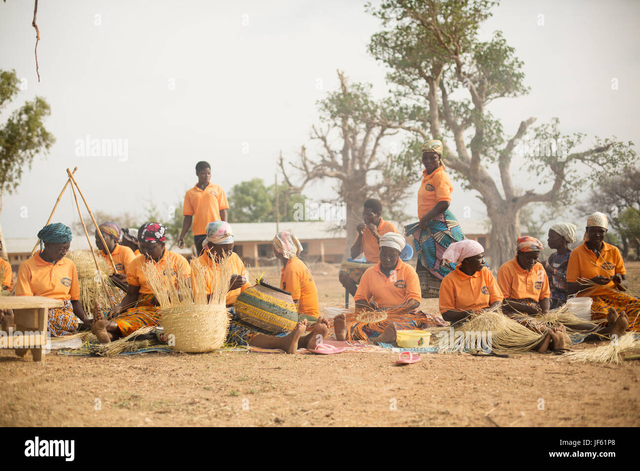 Le donne da un tessitore cooperativa tessere tradizionali cesti di paglia insieme nella Upper East Regione, Ghana. Foto Stock