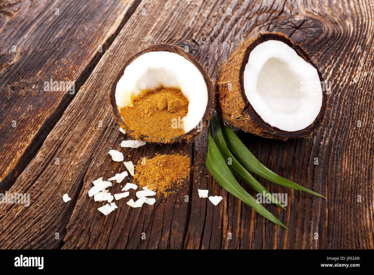 Lo zucchero di cocco. Fresco e salutare halfs cocco sul tavolo in legno con foglie. Foto Stock