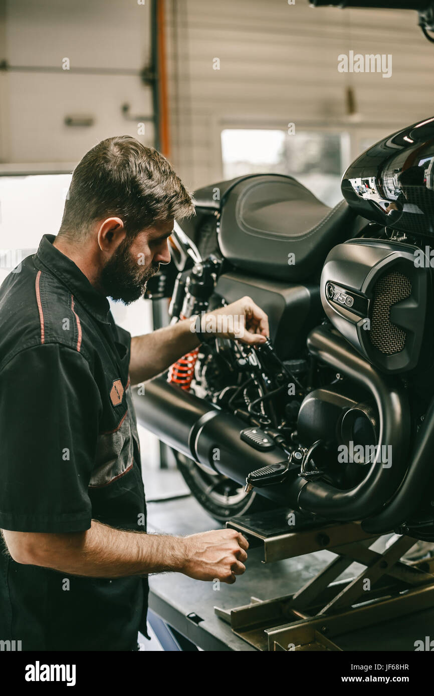 Professional bike meccanico controlla il livello di olio del motociclo. La moto sportiva è sul sollevatore. Foto Stock
