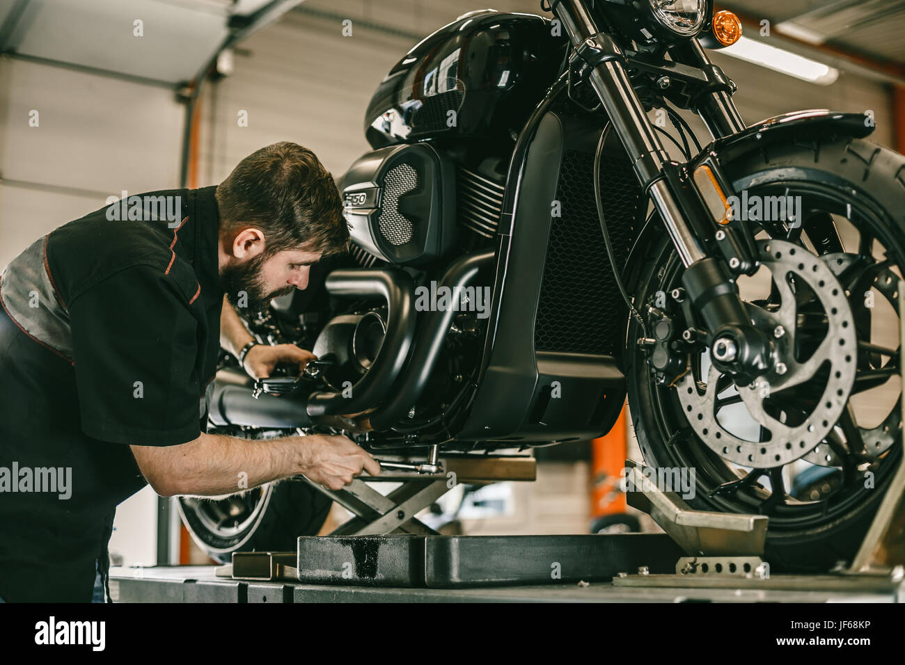 Meccanico professionista cambiare l'olio in una motocicletta. La moto sportiva è sul sollevatore. Foto Stock