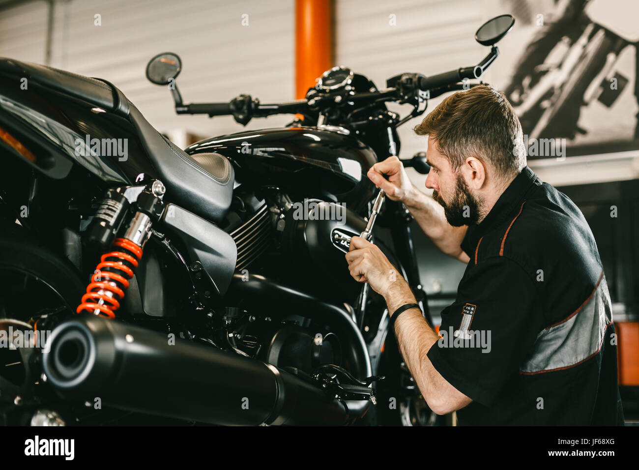 Meccanico professionista lavorando un cacciavite e riparazione di moto. Bel  giovane la riparazione di moto nel negozio di riparazione Foto stock - Alamy