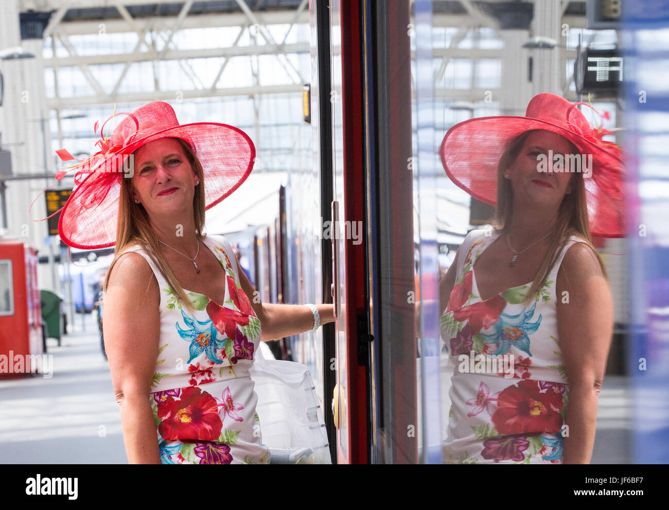 Una donna in Red Hat a Londra Waterloo assi un treno sul suo modo di Royal Ascot sul Signore giorno Foto Stock
