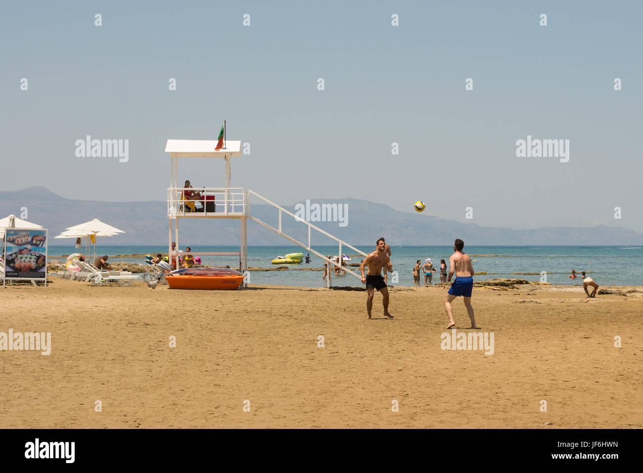 Giovani uomini la riproduzione di calcio sulla spiaggia sulla spiaggia di Agia Marina, Creta, Isole Greche, Grecia Foto Stock