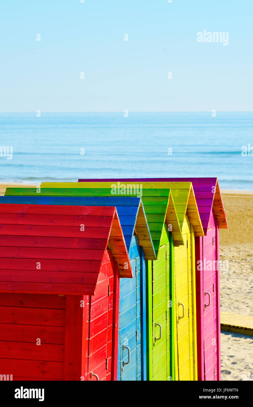 Primo piano di alcuni pittoresca spiaggia di capanne di colori diversi in una spiaggia solitaria, con l'oceano sullo sfondo e uno spazio vuoto sulla parte superiore Foto Stock