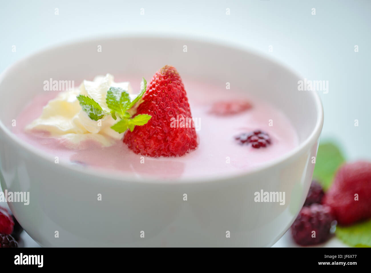 Fresca zuppa di berry closeup con Fragola, foglia di menta e della crema di latte Foto Stock