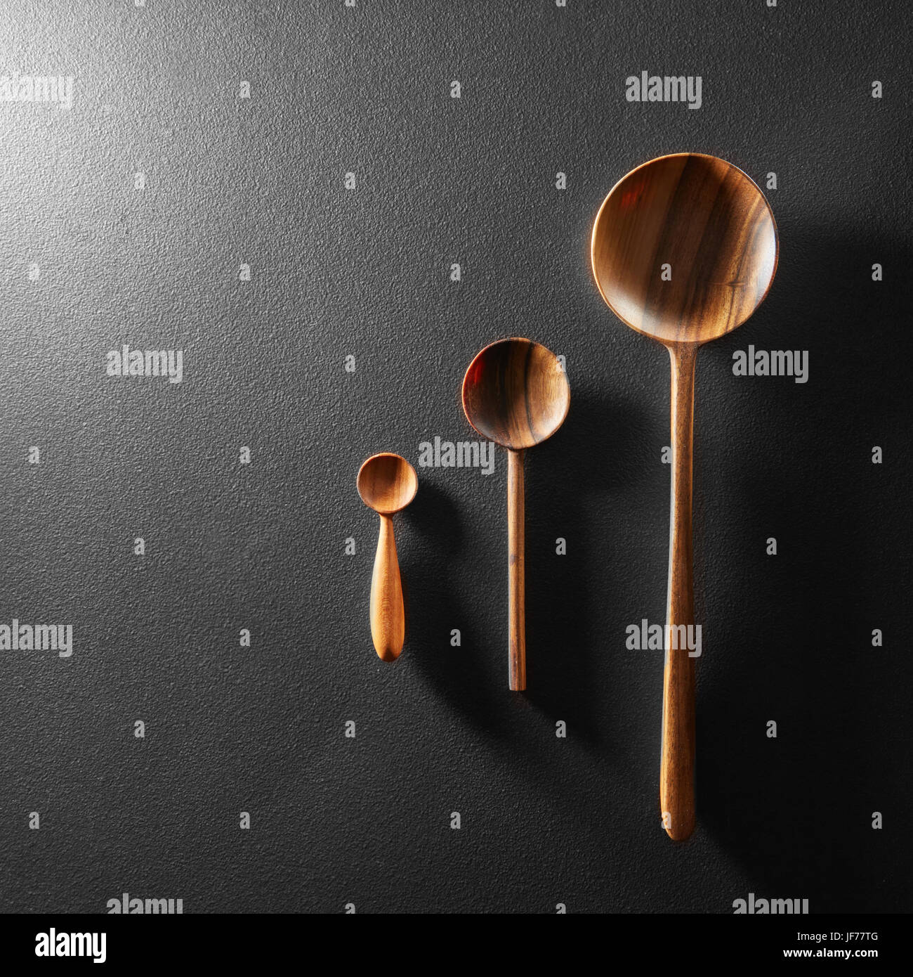Cucchiai di legno nero su sfondo della scheda Foto Stock