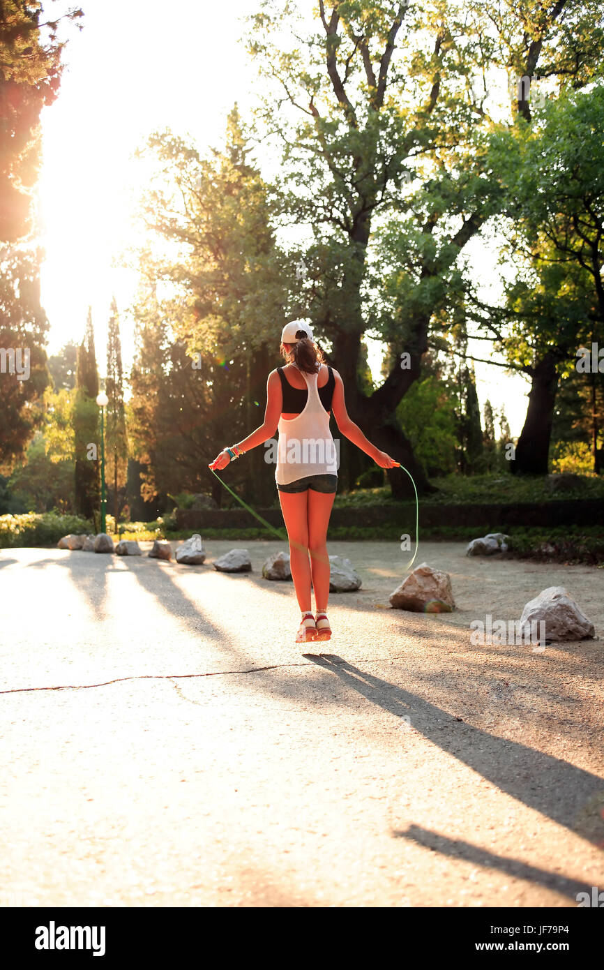 Bellezza svelte ragazza adolescente salto con la corda nel parco di mattina Foto Stock