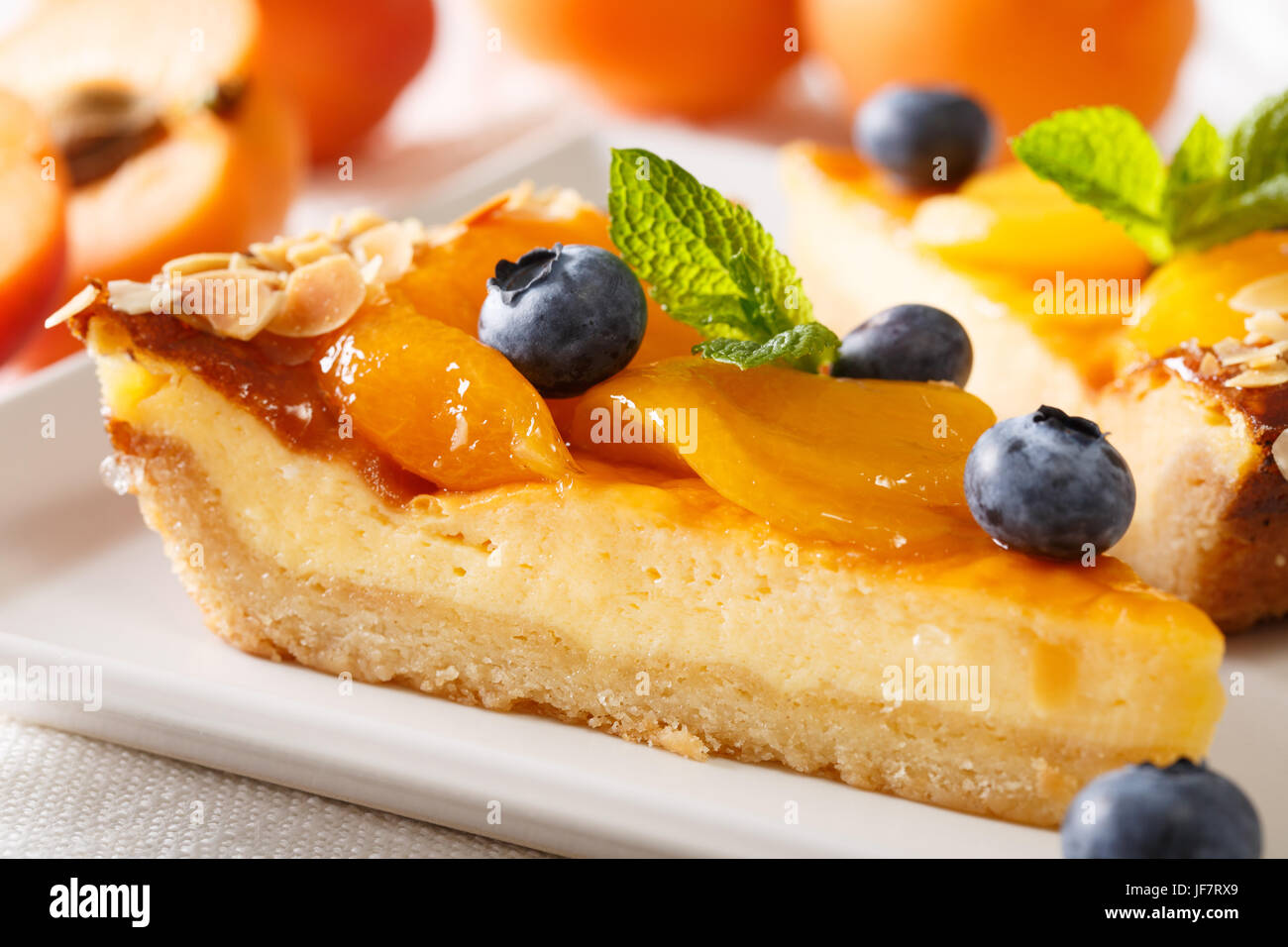 Un bel dessert: una cheesecake con albicocche, mirtilli e mandorle close-up su una piastra orizzontale. Foto Stock