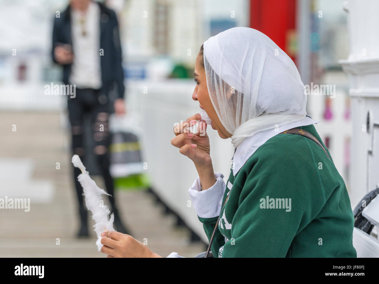 Donna asiatica di indossare un velo seduto fuori a mangiare nel Regno Unito. Foto Stock