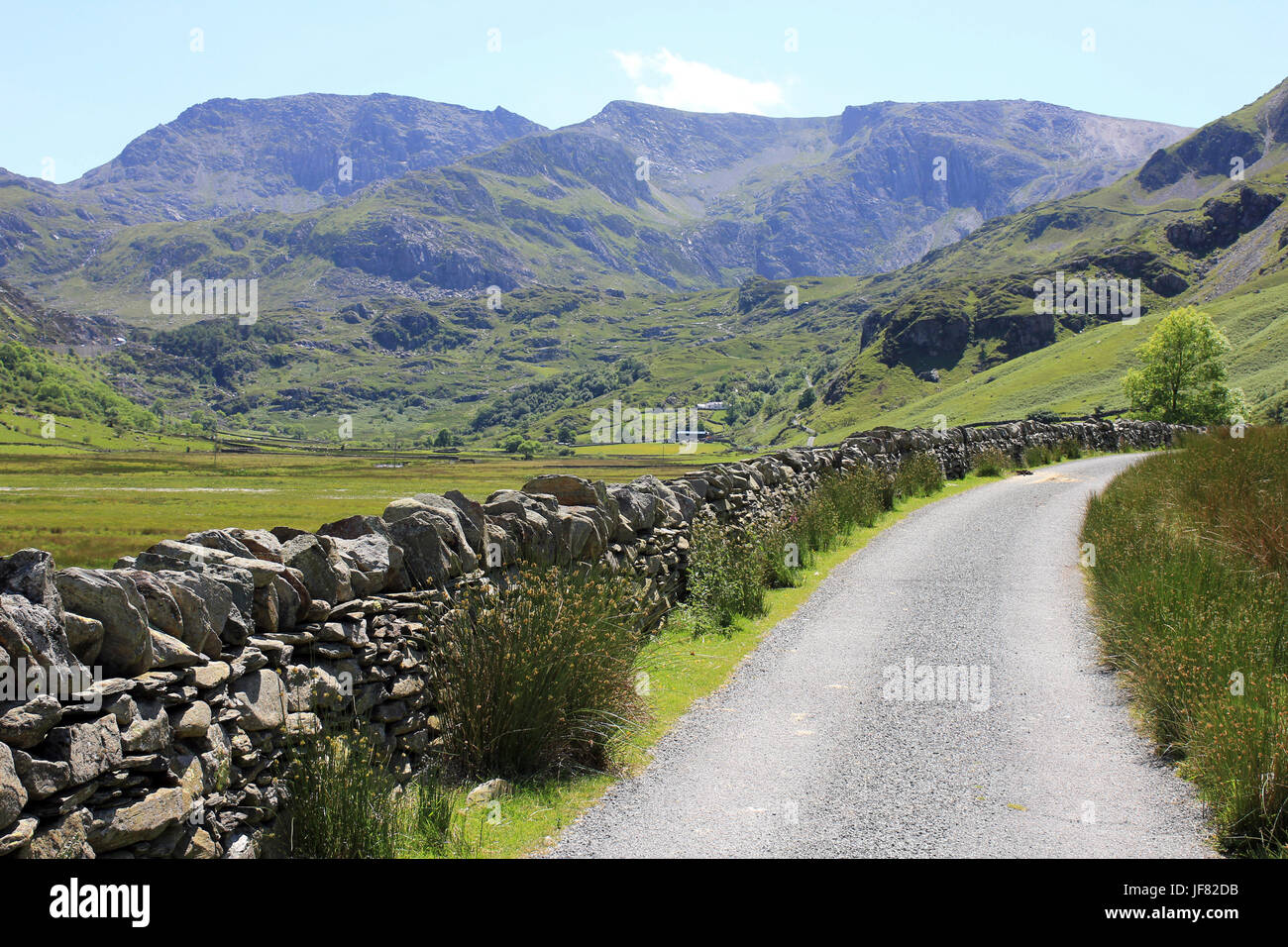 Strada che costeggia il Nant Francon Valley, Snowdonia, Galles con picchi di Glyder Fawr e Glyder Fach come sfondo Foto Stock