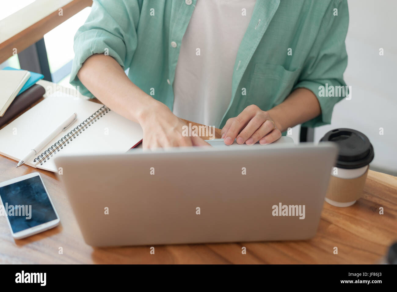 Asian hipster maschio con panni casual digitando su laptop tastiera del computer mentre si lavora nella caffetteria sulla giornata lavorativa. freelancer stile di vita e la nozione di attività Foto Stock