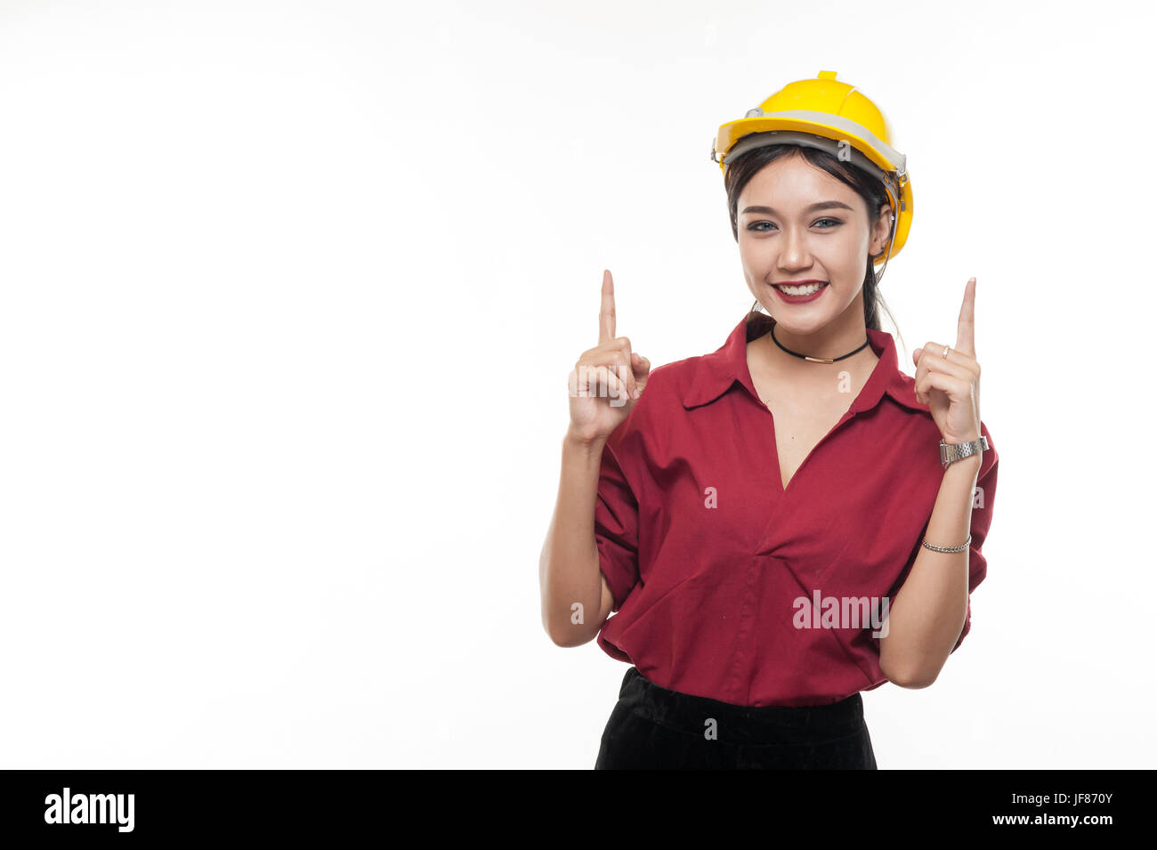 Donna asiatica ingegnere in maglietta rossa e gialla cappuccio di sicurezza sopra di puntamento con felice commozione. Persone gesticolando in business e concetto enginerring Foto Stock