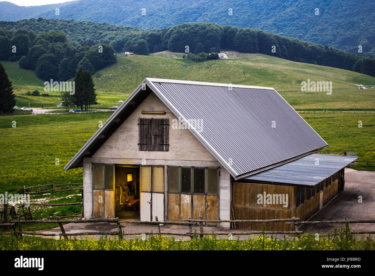 Edificio rurale con maneggio interno con prati, boschi e colline in background. Foto Stock