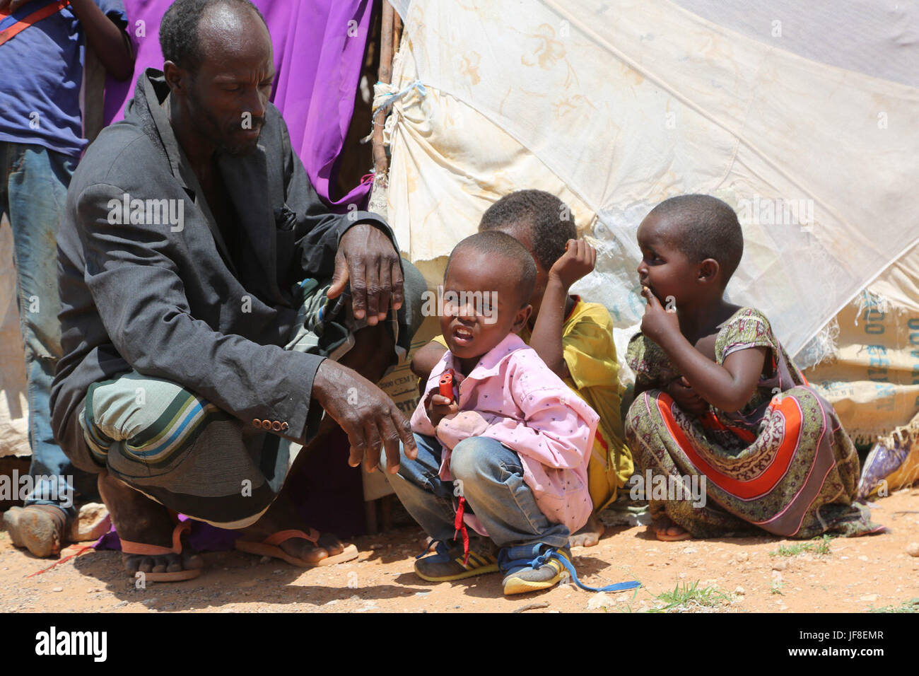 Abdi Amalow Yusuf si siede con i suoi figli davanti alla loro tenda realizzato localmente in Beletweyne, Somalia, il 28 maggio 2017. AMISOM foto Foto Stock