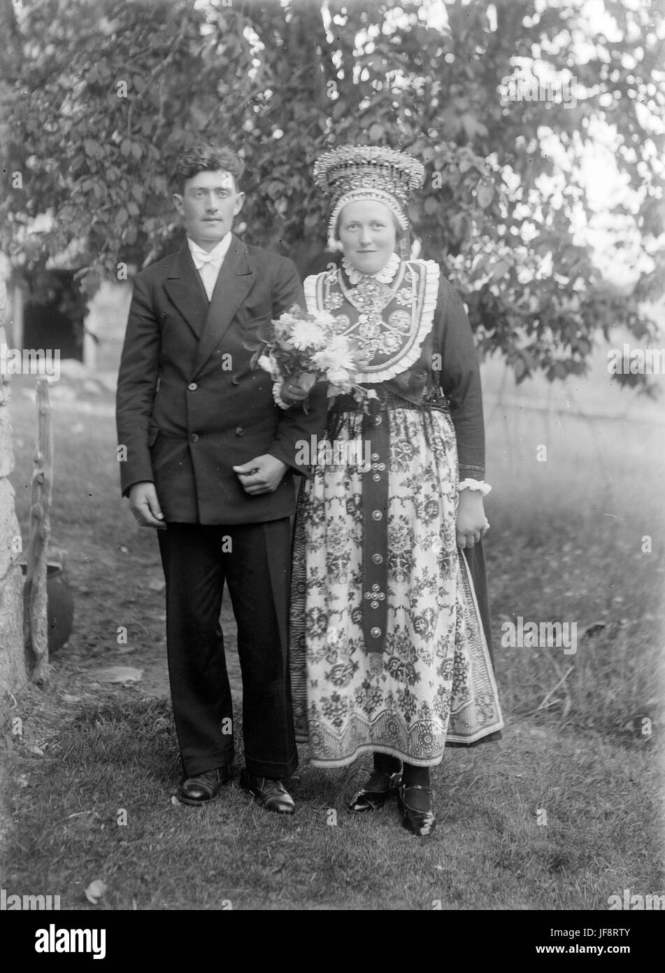 Una fotografia vintage di una sposa e sposo degli anni '1930, che mostra il loro tradizionale abbigliamento da sposa, con una corona nuziale e costumi nazionali. Foto Stock