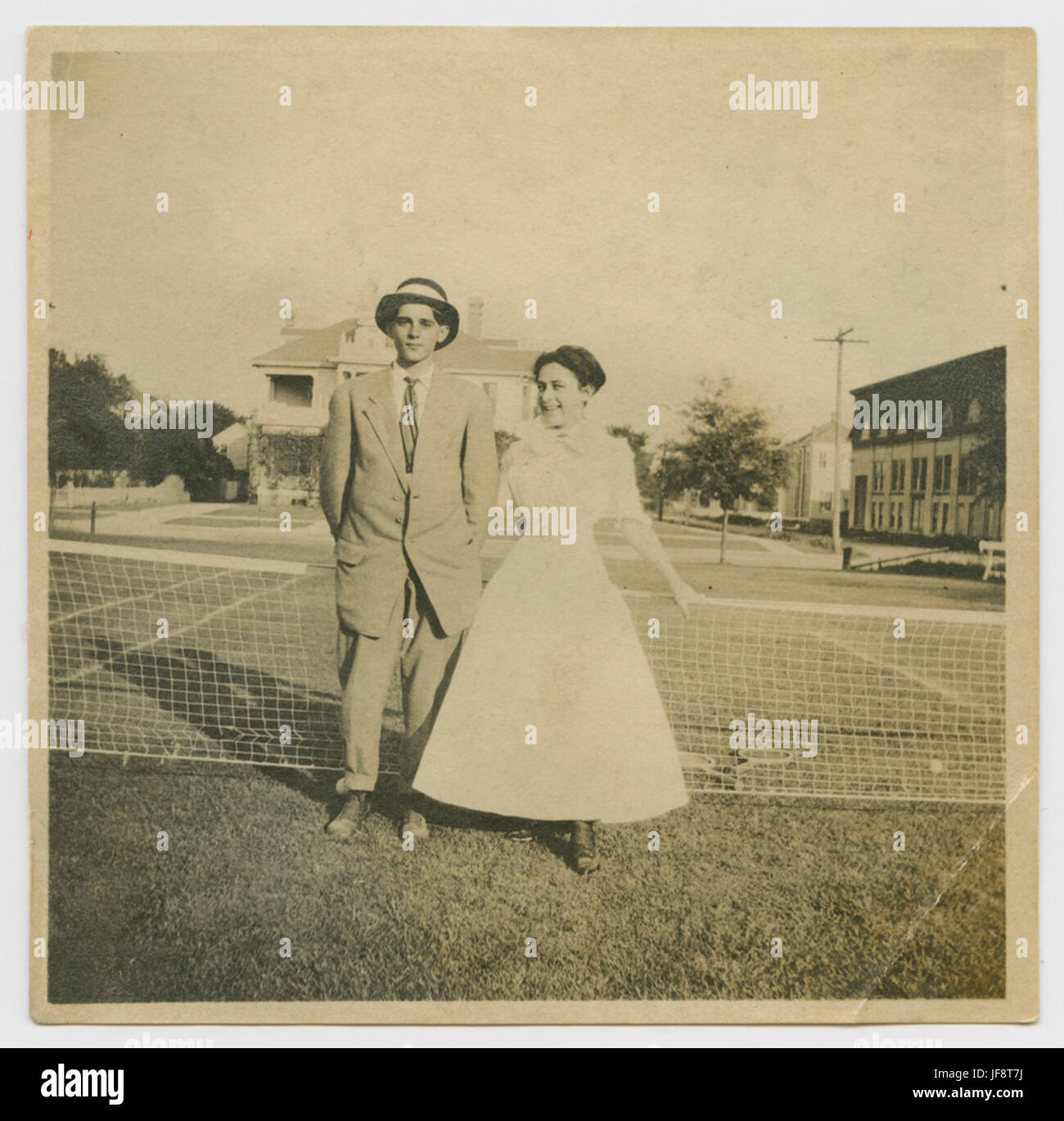 Una foto di moda che mostra un uomo che indossa una tuta e un cappello a banda larga con una donna, forse in occasione di un evento di tennis o di un incontro sociale. Foto Stock