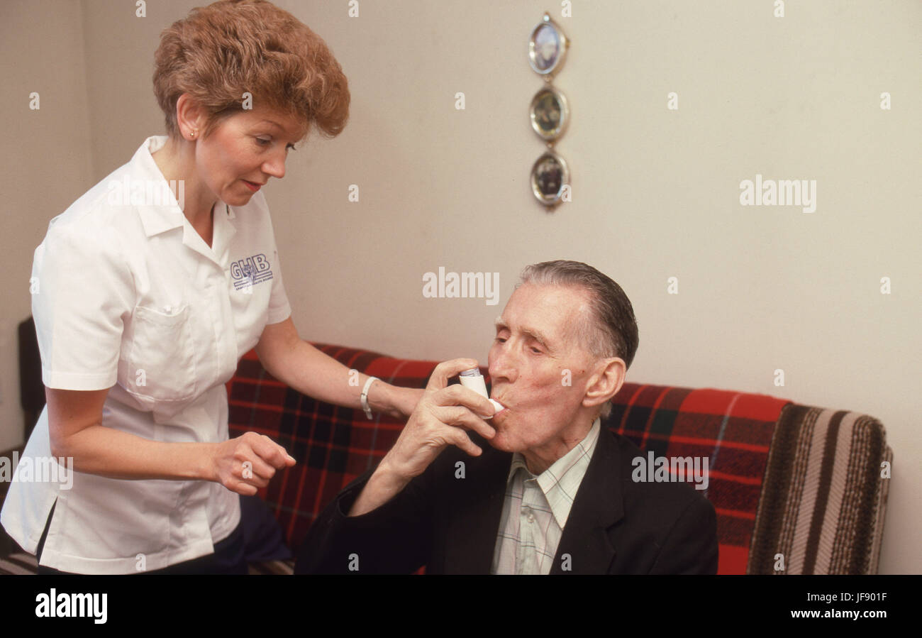 Visitatore di salute assistere uomo anziano con il suo farmaco di asma in alloggi protetti Foto Stock