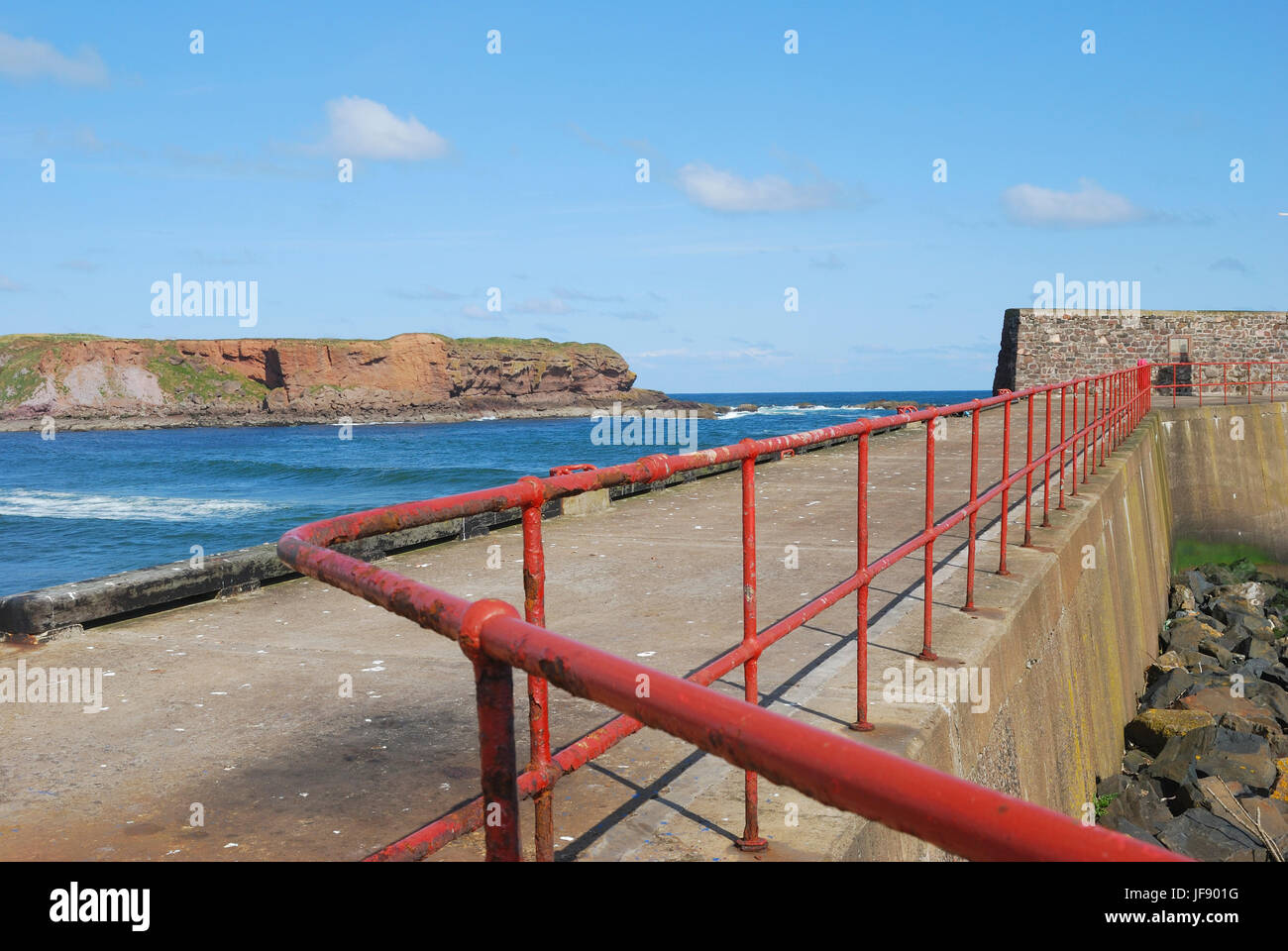 Parete di porto, ringhiere, il mare e le scogliere a Eyemouth, Berwickshire Foto Stock
