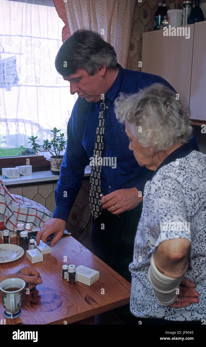 Home Visita da GP assistere anziani donna con le sue medicine Foto Stock