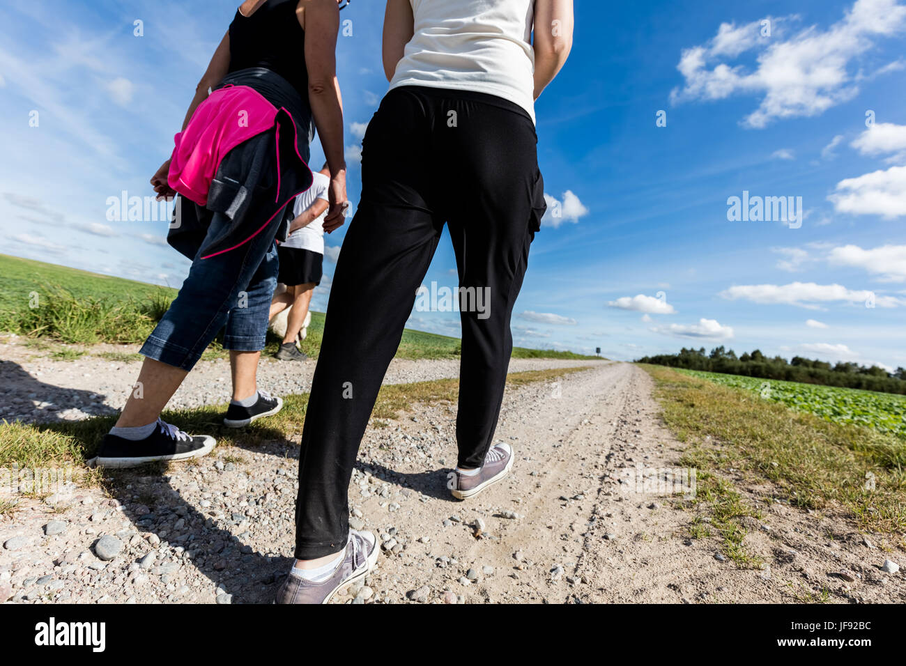 Famiglia a piedi in campagna in una giornata di sole. Gambe prospettiva, ampio angolo. Foto Stock