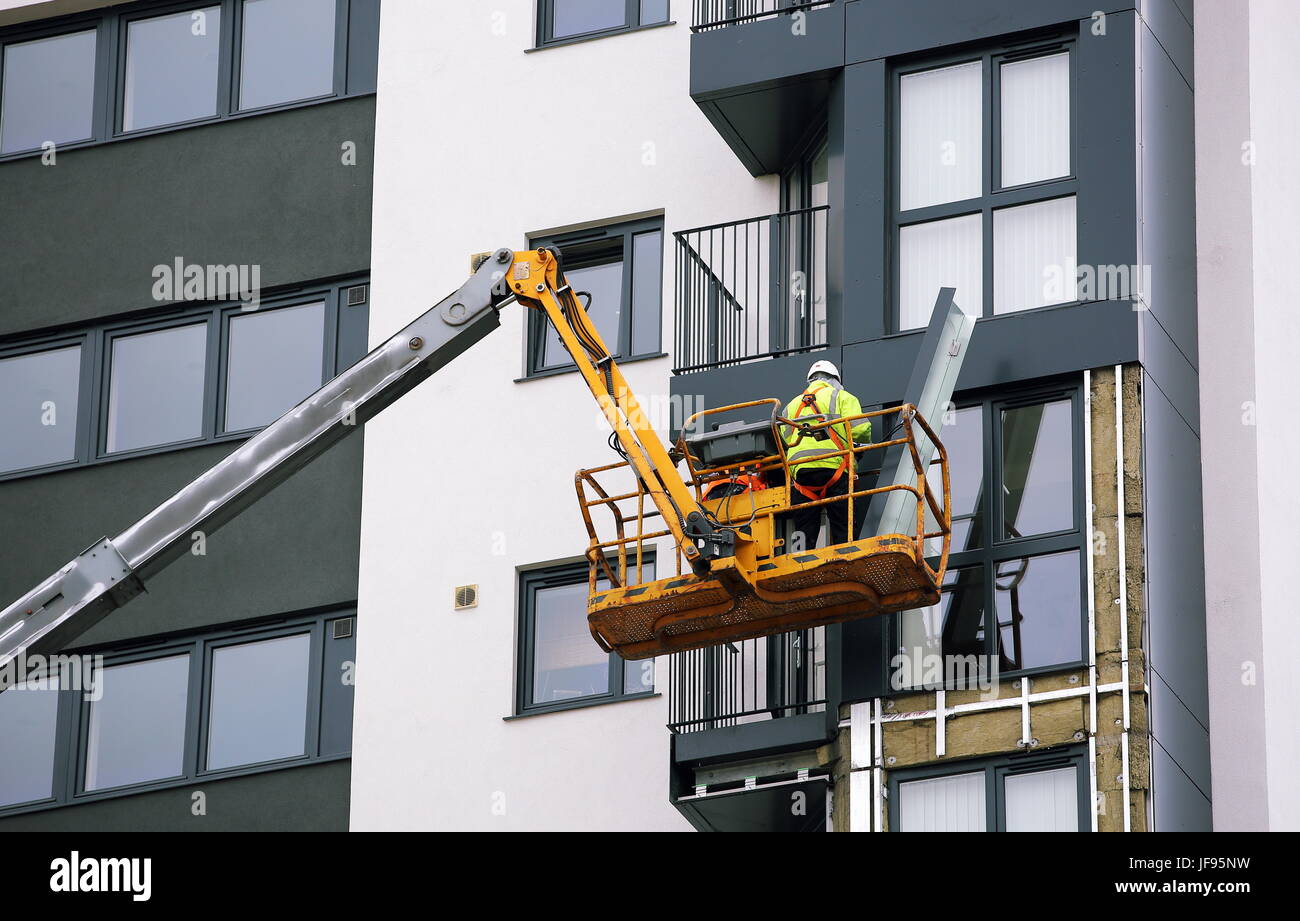 Lavoratori su un cherry picker rimuovere pannelli di rivestimento da Kennedy Gardens flats in Billingham Foto Stock