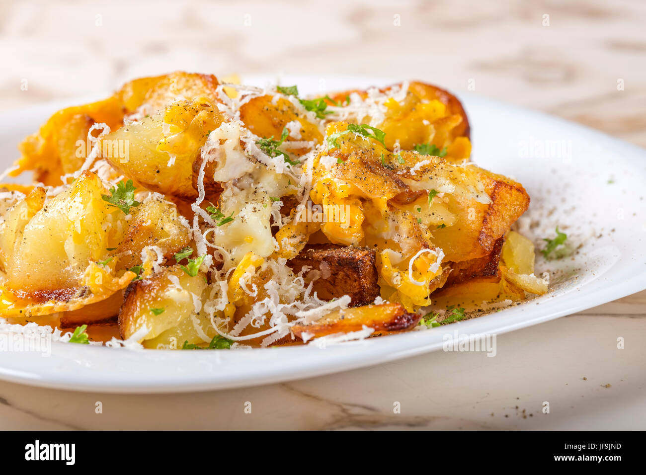 Patate fritte con uova strapazzate e parmigiano sulla piastra bianca Foto Stock